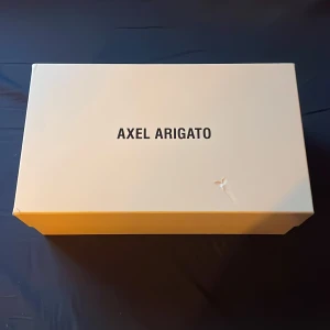 Skokartong-axel arigato - ⚡️Axel arigato skokartong.  Litet hål i höger hörn på toppen av lådan. Priset prutbart vid snabb affär. Köparen står för frakt (39kr) ⚡️