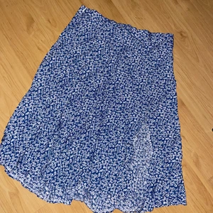 Blommig kjol  - Kjol med slits. Superfin och skön. Riktig sommarkjol och fin fin blå färg. Storlek L men lite mindre i Strl så passar även M