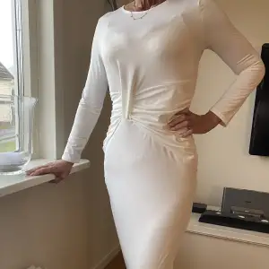 Oanvänd lång vit klänning med design framtill
