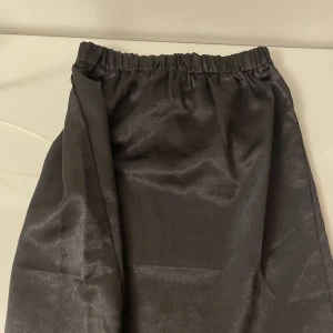 Satinkjol - Svart satinkjol med resår i midjan och slits på båda sidor. Går precis över knäna på mig som är 172 cm💃🏼