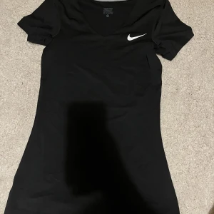 Nike T-shirt  - En träningstshirt från Nike pro som enbart är använd ett fåtal gånger! Supermjukt och glansigt material och i strl Xs. En slimfit modell med v-ringning 🥰