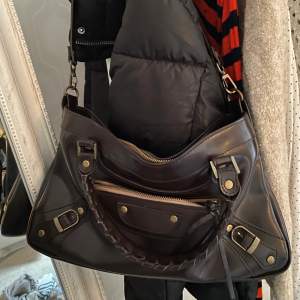 Balenciaga ”liknande” väska med ett band som går att ha både som handväska och crossbody bag! 💕brund/svart färg! inga defekter alls! Säljer billigt endast för att jag har så många väskor