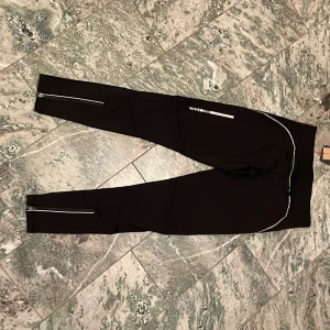 Träningstights svarta Pro touch - Svarta träningstights PRO touch med redlexdetaljer. Inköpta oprövade på rea. Aldrig använda då de var för små. Prislappen är kvar.