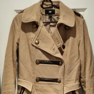 Fin beige kappa från H&M, med militärinspirerad design. Buren ett fåtal gånger, normal i storleken. :)  Storlek 36