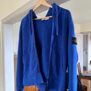 Stone Island Zip Hoodie - Blå Zip hoodie i bra skick. Inga fläckar eller andra skador. Alltid tvättats i 30 grader utan stone island badgen. Köpt för ca 5 år sedan från Van Mildert. Skicka ett meddelande till mig för att få tillgång till authenticity koden.