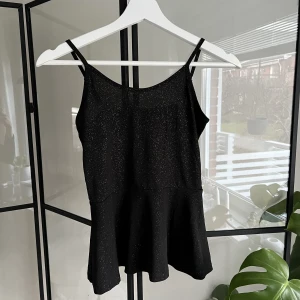 Topp - Glittrig svart topp i storlek 146/152 som även passar xs/s. Toppen är endast använd ett fåtal gånger och är i väldigt bra skick!