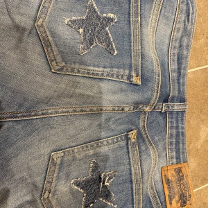 Lågmidjade jeans - Säljer dessa ursnygga lågmidjade bootcut jeans me stjärnor på bakfickorna! Säljer de de tyvär är lite för små!! De har några små hål på innerbenet men inget man lägger märke till!! Kontakta för fler bilder eller frågor!!😻