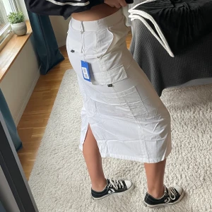 Cargo skirt  - Lång vit cargo skirt super snygg och fylld med coola detaljer🤩 vit färg aldrig använd så ser ut som ny och är inte genomskinlig🙌 köpt från Sellpy mycket bra skick! Strl 42 säljer för 150kr + frakt