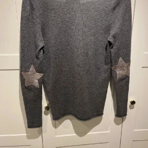 Zadig tröja - grå stickad tröja från zadig & voltaire! passar mig är storlek S/XS Fint skick. Kragen är V ringad  men kan ochså dras ner till off shoulder, stjärnorna sitter på armbågarna.