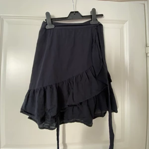 Svart kjol  - Svart omlottkjol i storleken 38/M 🖤🖤 har jättefin detalj på volangen 