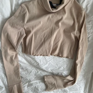 Beige Crop top - En beige croptop med hög krage och bell armar. Ribbad