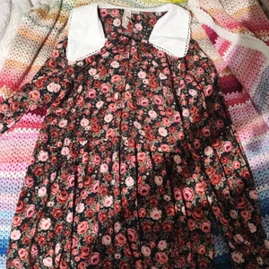 Blommig klänning - Blommig klänning med krage och knappar framtill. Storleken är M eller liten L