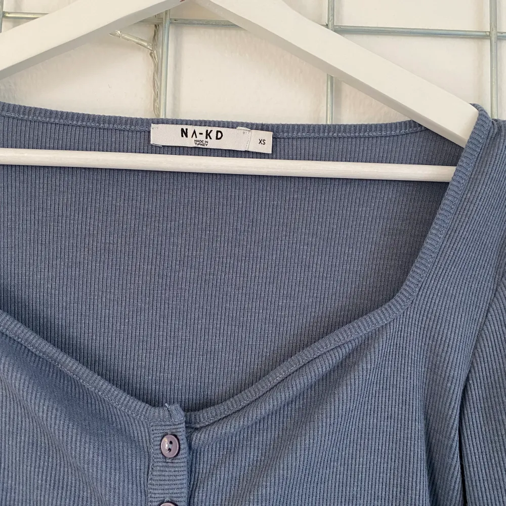 En långärmad tröja från NA-KD. Blå-grå nyans i ribbat material. Button up. Köpt i våras men tyvärr knappt använd. Storlek XS men passar mig som vanligt när S.. Toppar.