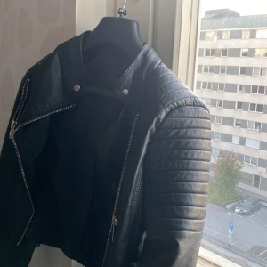 Skinnjacka - Säljer min skinnjacka eftersom den inte kommer till användning och har blivit för liten för mig. En väldigt fin skinnjacka. Köpt för 700kr på chiquelle. Jackan är i väldigt fint skick. Inte äkta skinn! Jackan är i storlek L men sitter som M