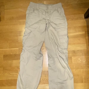 Beiga cargo byxor från hm - Beiga cargo byxor som inte används längre. Stretchiga vid midjan så man kan välja vart man vill att dom ska sitta. Bra kvalite och storlek 34 från divided, hm.