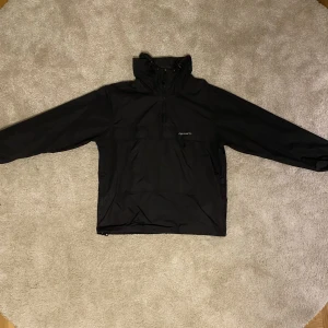 Svart Carhartt Vindanorak jacka - En svart Carhartt Vindjacka i ganska använt skick (7.5/10) Storlek M. Pris kan diskuteras vid snabb affär. Kan hämtas i Uppsala och kan frakta