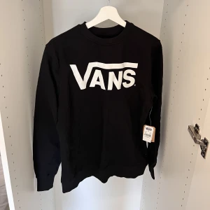 Klassisk svart Vans Sweatshirt för män - Nyhet! - Uppgradera din avslappnade garderob med denna klassiska svarta Vans crew-tröja för män. nyskick, med den ikoniska logotypen på bröstet. Bekväm, trendig och perfekt för alla tillfällen. Ta tag i det nu och höj ditt stilspel!