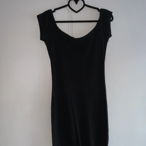 Svart klänning  - En lång svart axelklänning med en fin urringning i storlek small. Den är tunn och skön, 60% polyester. 