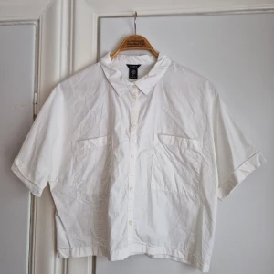 Kortärmad bomullsskjorta (NY!) - Kortörmad och lite bred bomullsskjorta från Lindex. Ny och oanvänd!  Kort och bred i modellen.  Stl L / 42 / 44.  Riktigt snygg till högmidjade jeans och kjolar. Även klänning såklart!  Klänningen på bilden är till salu och finns i en annan annons. 