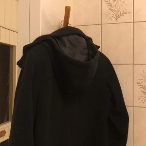 Svart kappa stl 38  - Svart kappa från H&M stl 38. Fint skick. 60 % ull, 30 % polyamide, 10 % cashmere. Säljes i befintligt skick. 