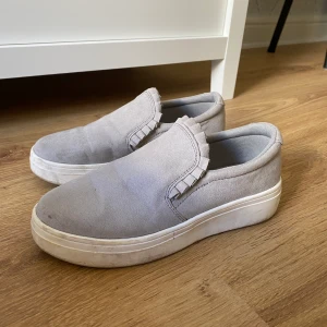 Kallgråa slip-on skor  - Säljer mina kallgråa slip-on skor. Dom är så fina till rätt person men de passar ej min stil längre. Har används några gånger ute men det är inga grova märken mer än smuts som är lätt att ta bort. 