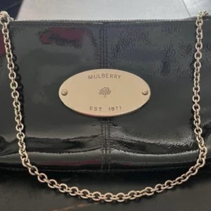 Mulberry väska  - Väska i lackerat svart läder med silveremblem fram. Handtag i silverkedja. Köpt på NK.  Mycket bra skick. 