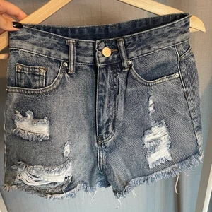 Jeansshorts - Jeansshorts från shein, är blåa i verkligheten men ser ut som grå nu på bild, är en stl xs men sitter som en S, tighta i midjan o stora i benen, satt inte snyggt på mig som är en xxs-xs