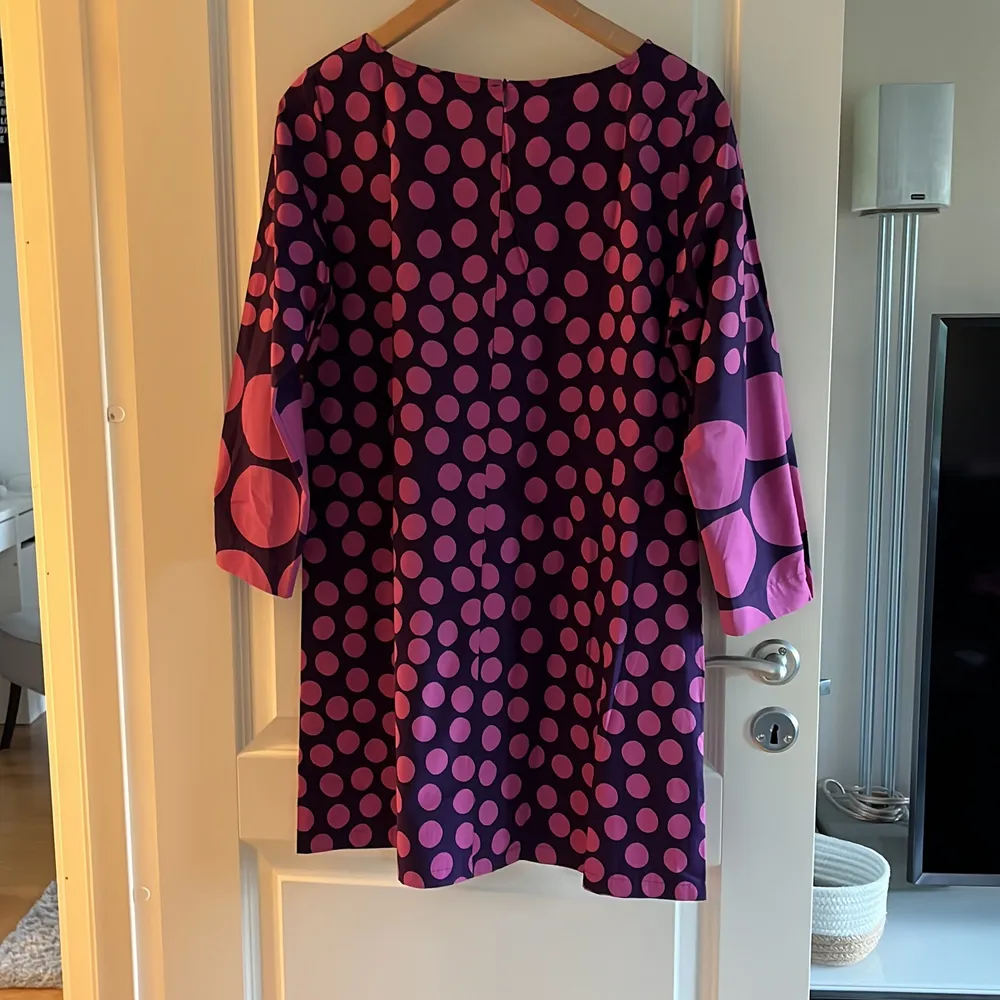 Klänning från Marimekko, lila med rosa prickar, strl 38, bomull, blixtlås i rygg, fickor i sidsöm, knapp vid ärmslut Köpare står för frakt. Klänningar.