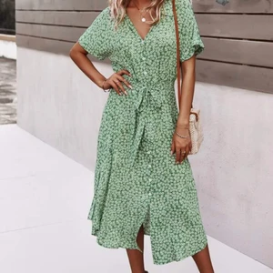 Grön klänning - Grön klänning med blommor och knappar och ett band i midjan. Perfekt för sommaren, använd fåtal gånger och den är jättebekväm och har stretch i midjan.