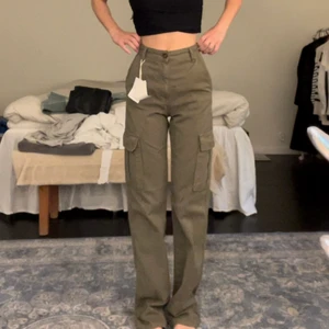 Gröna cargo pants - Säljer ett par gröna cargo pants från Stradivarius som aldrig är använda, prislappen sitter kvar. Jag är 163cm☺️  Frakt tillkommer!💘
