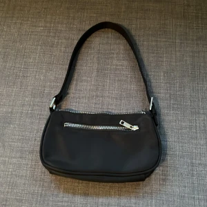 Svart väska - Svart väska som är perfekt till sommarn! Kommer tyvärr inte ihåg vart den är köpt  Tålig och smidig! Frakten ingår ej i priset för väskan!