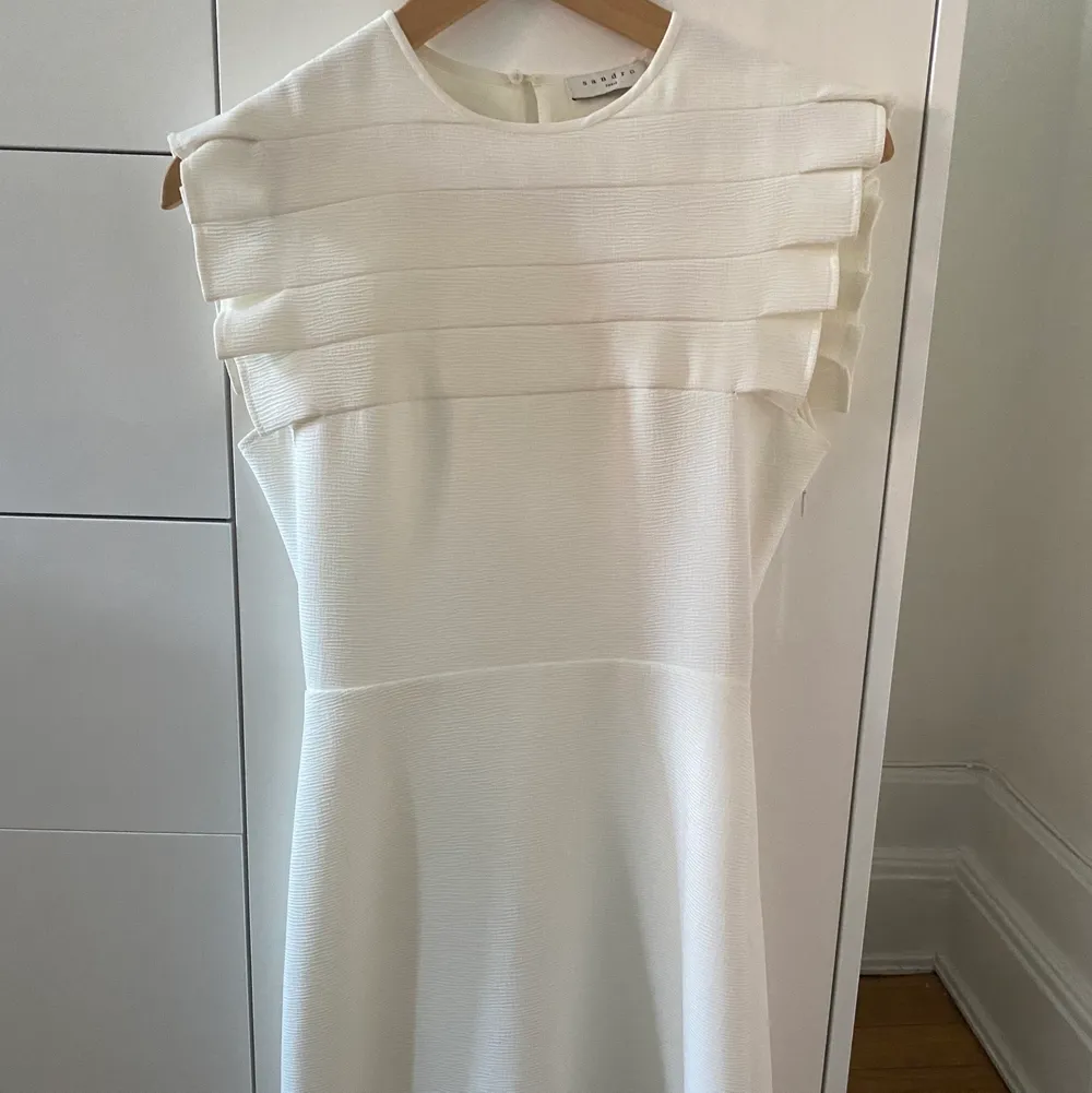 Säljer denna vita Sandro klänningen i storlek 34/XS i modellen ”Laurena”. Perfekt som studentklänning eller konfirmationsklänning eller examensklänning! Köpt för ca 2500kr och endast använd en gång och är därför så gott som i nyskick! Hör av er vid frågor!:). Klänningar.