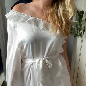Klänning - Vit one shoulder klänning som är perfekt nu till sommarn eller till studenten. I storlek 38 men eftersom resåren är stretchig och det är band i midjan så passar klänningen de flesta storlekar:) Använd endast en gång så nästan i nyskick. 