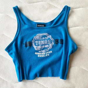 Blått y2k linne  - Blått linne med coolt tryck. Strl 128 men passar mig som har XS. Inga hål eller fläckar, men ser lite nopprig ut om man kollar noga med det är inget som syns. Köpare står för frakten! 