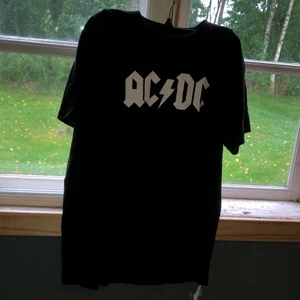 Ac/dc T-shirt  - Detta är en ac/dc T-shirt. Motivet är fin men på botten av tröjan så har tråden börjat lossna (syns på bild 3). Det borde gå att fixa den med en symaskin!