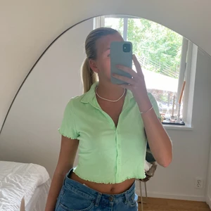 Grön tröja  - Säljer denna jättefina limegröna t-shirt med krage och knappar. Helt oanvänd med lappen kvar. Köpt på H&m för 150kr. 