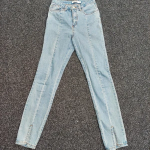 Jeans med slits  - Blå jeans med söm och slits framtill. Använda ett fåtal gånger. Stl.32. Från NA-KD 