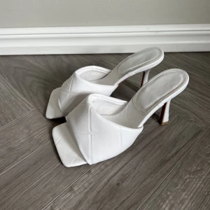 Vita mules klackskor! - Vita ”quiltade” mules! Strl 36. Ca 8-10 cm klack. Har använts och har små slitningar framtill, dock knappt synliga från håll. 