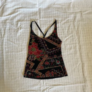 Linne med mönster  - Svart linne med mönster. Har band man justerar i bak. Står ingen storlek men skulle säga S men passar även M