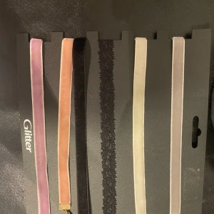 Set med fem choker-halsband från Glitter - Ett set med fem choker-halsband från Glitter i olika färger och material. Setet innehåller ett rosa, ett beige, ett svart spets, ett vitt och ett ljusrosa halsband.
