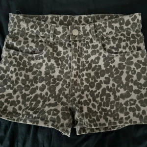 Leopardmönstrade shorts från H&M - Ett par leopardmönstrade shorts från H&M. Shortsen har en knapp och dragkedja framtill samt två framfickor. De är låg midjade och har en normal passform.