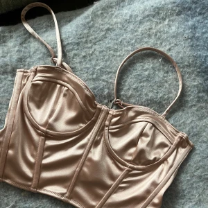 H&M korsettopp i satin - H&M korsettopp i satin. Den är mer puderrosa än vad bilden visar. Säljer då jag inte använder längre. Jag är 170 cm lång och bär oftast S i toppar och M-L i byxor 💕