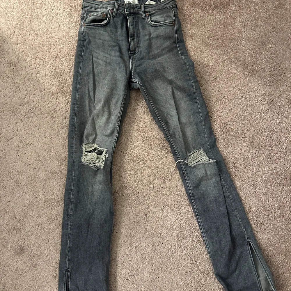 Gråa Zara jeans med slitningar och slits nertill . Jeans & Byxor.