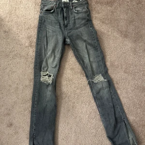 Gråa Zara jeans  - Gråa Zara jeans med slitningar och slits nertill 