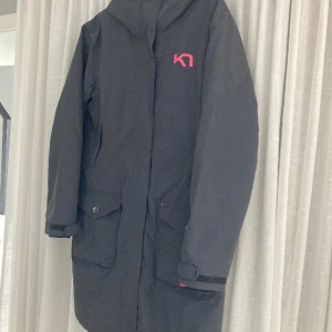 Kari traa parkas stl XL - Grå lång jacka med löstagbart foder (knäpps fast i ytterjackan) i rosa som separat går att använda som jacka. 3-i-1 jacka med andra ord. Något tvättblekt samt lite noppror på sidorna där ärmarna gett slitage.