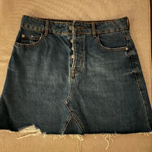 Jeanskjol Bershka - Snyggt sliten jeanskjol från Bershka med knäppning. Storlek 40.