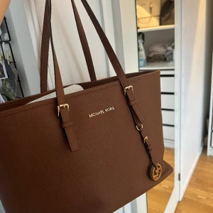 Michael kors väska brun  - Jag säljer min äkta Michael kors väska då jag inte använder den längre ink skyddspåsen.  I mycket bra skick, inga skador eller liknande  Nypris  3499kr säljer för 600kr  Kan mötas upp i Stockholm eller fraktas 😊