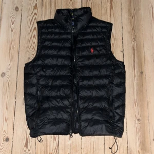 Ralph lauren väst - Svart Ralph Lauren väst till salu i väldigt bra skick! Perfekt inför våren. Västen är iprincip i nyskick utöver en lagning som är professionellt lagad och dessutom osynlig vid andvändning. Den är i storlek S men sitter nästan lite mer som M!