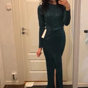 Grön festklänning Bubbleroom - Mörkgrön skimrande maxiklänning från bubbleroom. Kan bäras med ’knytningen’ både fram och bak. Aldrig använd, prislapp kvar. Slits upp till knät på sidan. Är fodrad från midjan och ner. Inte alls tung i matrialet. Nypris 900kr. Strl XS. 