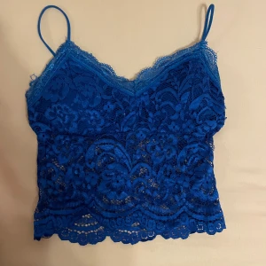 Blå spetslinne - En blå spetslinne med smala axelband och v-ringning. Linnet har ett blommigt spetsmönster och är padded för extra stöd. Skriv gärna om ni har frågor 💕